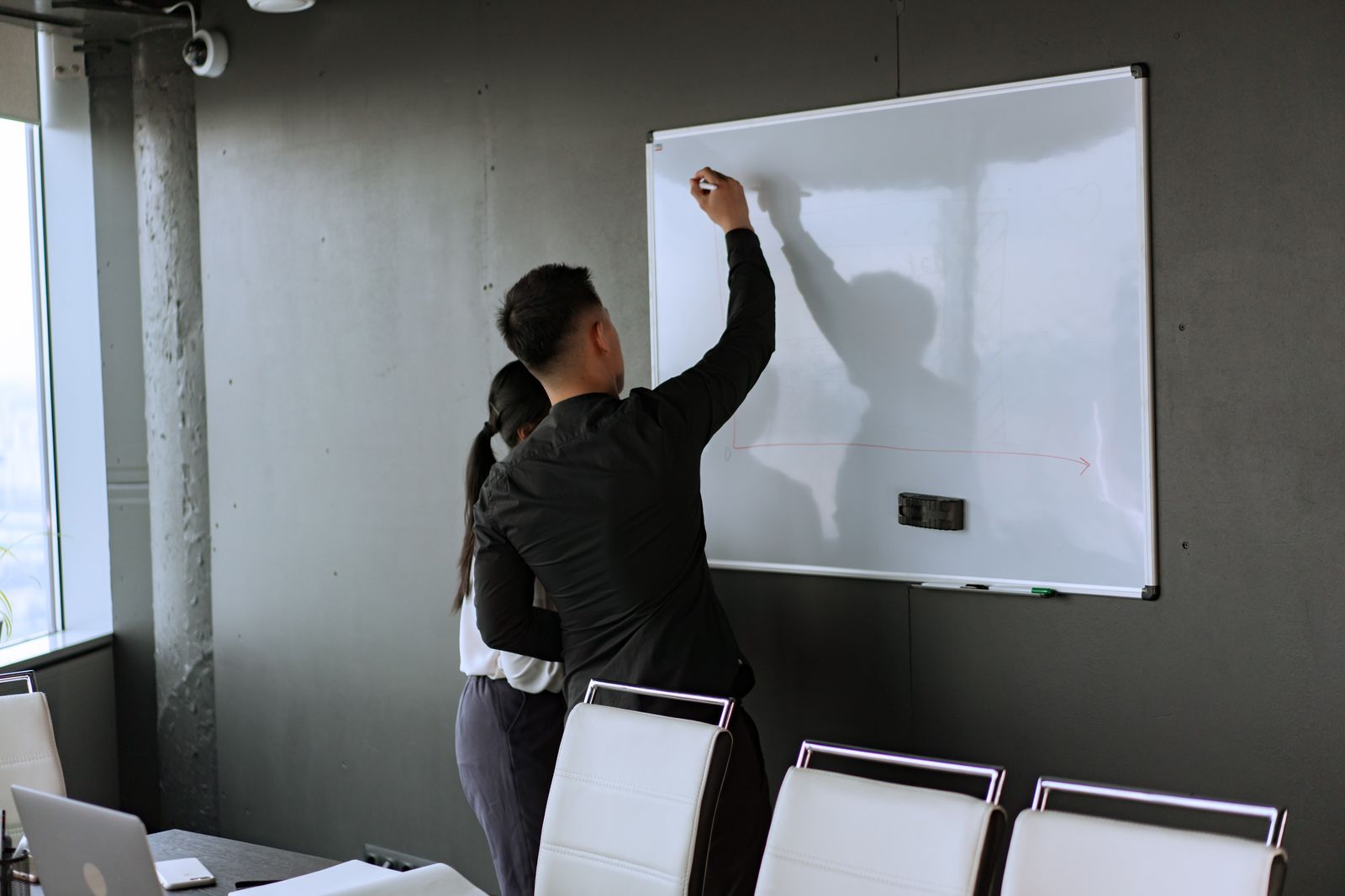 Two colleagues brainstorming at a whiteboard